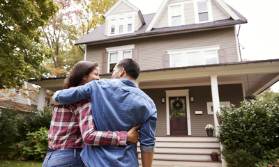 Male and female couple embracing walking towards first home