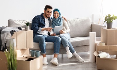 Man and woman sitting on living room couch with moving boxes on floor