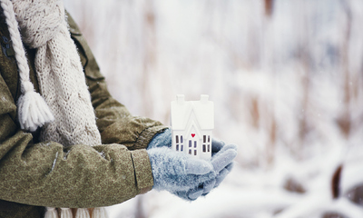 Woman standing holding decorative miniature home in snowy weather