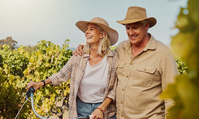 Happy senior couple walking together through vineyard