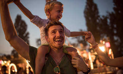 Boy on father's shoulders enjoying summer festival